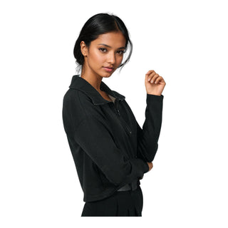 A serene woman with dark hair and a subtle smile stands with her arms crossed, wearing a black EMF protective hoodie, portraying the garment's chic and functional appeal for protection against electromagnetic fields.