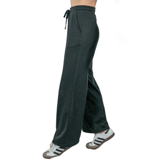 A side view of a person showcasing black EMF protective pants with a drawstring waist, paired with classic white and black sneakers, highlighting the pants' comfortable fit and functional design for everyday wear with electromagnetic field protection.