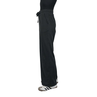 A side profile of a person wearing a black EMF protective pant with a drawstring waist and straight legs, paired with sporty white sneakers, emphasizing the comfortable and functional style designed for daily wear with electromagnetic field shielding capabilities.