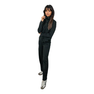 A woman models an elegant black EMF-protective turtleneck and pants set, designed to shield against electromagnetic fields, combining safety with style.