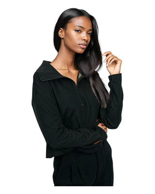 A woman models an elegant black EMF-protective turtleneck and pants set, designed to shield against electromagnetic fields, combining safety with style.